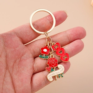 Detail of gold metal keychain with red MOM heart and rose charms held in hand