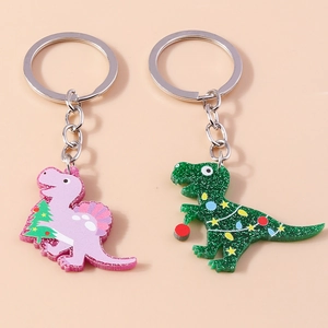 Detailed macro view of two glitter acrylic dinosaur keychains with festive Christmas themes