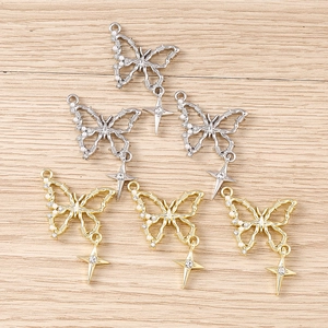 Detailed close-up of butterfly pendants with pearls and stars on a light wood background