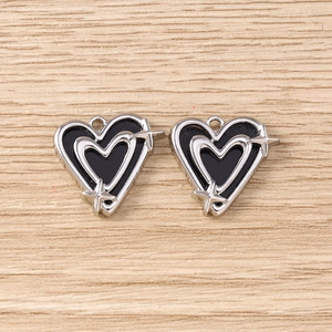 Detail von silbernen und schwarzen Emaille-Herzanhängern mit Sternen für DIY-Schmuck