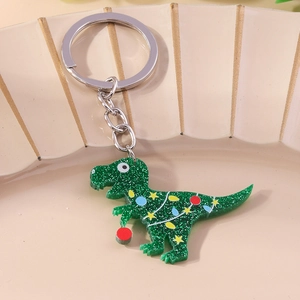 Close-up of a green glitter dinosaur keychain with festive patterns in a ceramic dish