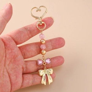 Porte-clés cœur doré chic avec strass roses et charm de sac à nœud perlé