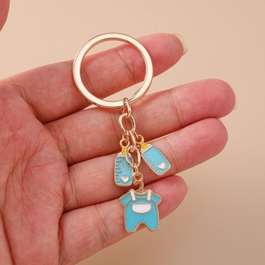 Detail of rose gold keychain with blue baby bottle and romper charms in oil-drop finish