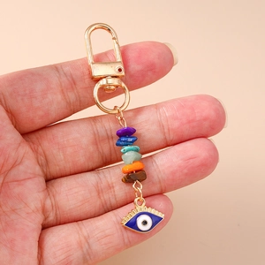 Close-up of bohemian evil eye keychain with colorful raw stones held in palm