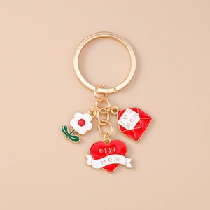 Detailed close-up of golden MOM keychain with red enamel heart and envelope charms