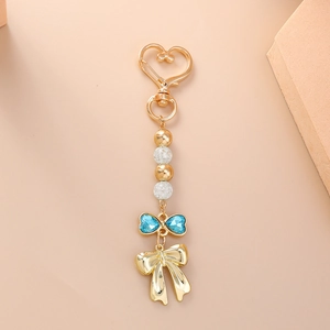 Détail du porte-clés nœud en strass bleu avec fermoir cœur doré et perles chic