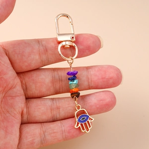 Detail of Hamsa hand keychain with colorful chakra stones and golden evil eye charm