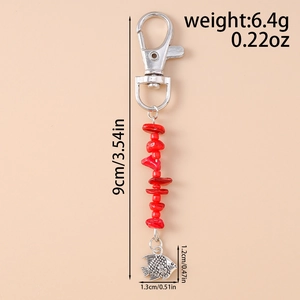 Detail of beaded keychain with silver fish pendant and red stones for bags and keys