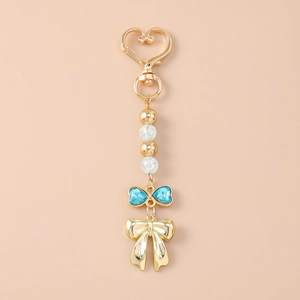 Détail d'un porte-clés à mousqueton coeur avec noeud strass bleu et perles en métal