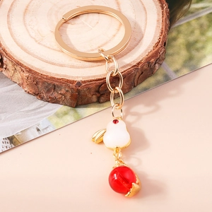 Chinese style golden rabbit keychain with white imitation jade and red bead on wood