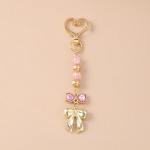 Détails de perles roses et fermoirs dorés en forme de cœur sur un porte-clés nœud élégant