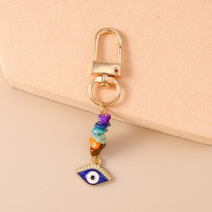 Detail view of colorful crushed stone evil eye keychain with golden lobster clasp and charms