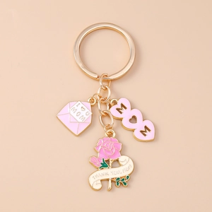 Close-up of golden MOM keychain featuring pink enamel rose, heart, and envelope charms
