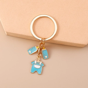 Detail of blue baby bottle and overalls charms on a golden metal keychain ring