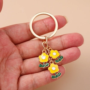 Porte-clés floral tendance avec trois fleurs en émail jaune et anneau en métal doré