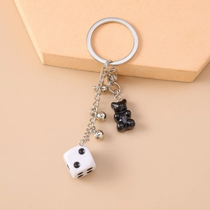 Close-up of black resin bear and white dice on a silver beaded keychain charm