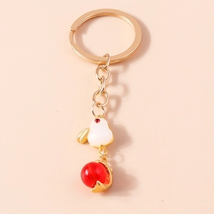 Close-up of cute white rabbit keychain with red bead and golden metallic ring