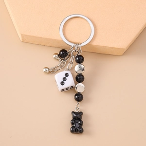 Detail view of the silver chain with a black resin bear and a white dice pendant keychain