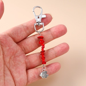 Detail view of handmade silver fish pendant with red stone beads and lobster clasp