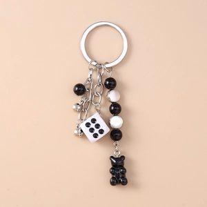 Detail showing the gummy bear charm, dice, and beaded chain on the metal keychain