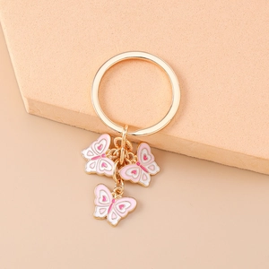 Dettaglio del portachiavi con farfalle in smalto rosa e bianco e anello in metallo dorato