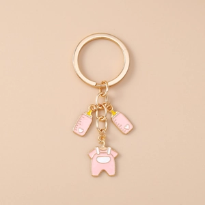 Close-up of pink baby bottle and onesie charms on a golden metal keychain link