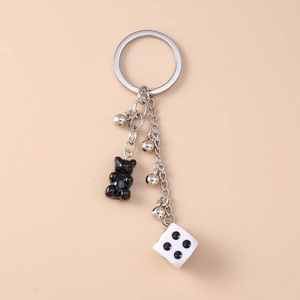 Detail of creative keychain with black resin bear, white dice, and silver bells pendant