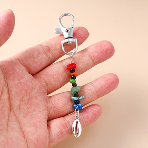 Ethnic style colorful beaded keychain with shell pendant held in hand for scale