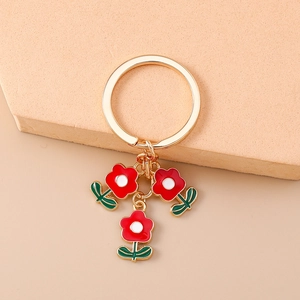 Détail d'un porte-clés floral avec breloques fleurs rouge blanc vert sur anneau doré
