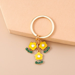 Détail d'un porte-clés floral doré avec des fleurs jaunes et des feuilles vertes