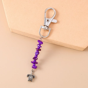 Detail of silver lobster clasp with purple stone beads and a metal turtle pendant
