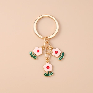 Détail de trois pendentifs fleurs roses avec anneau doré sur un fond beige minimaliste