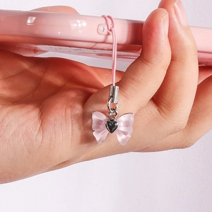 Detailed view of a pink bow phone charm with a silver heart on a matching case