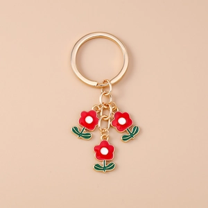 Vue détaillée du porte-clés fleur dorée avec pétales en émail rouge et tiges vertes