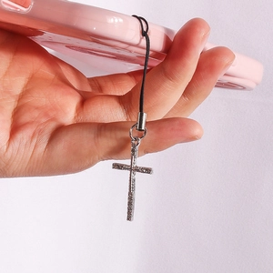 Detailed view of silver gothic cross phone charm with a textured metallic finish