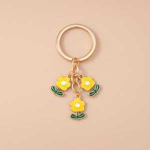 Détail du porte-clés doré avec trois breloques de fleurs jaunes et petites feuilles vertes