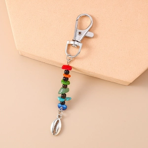 Detail of bohemian keychain featuring colorful stones and a silver seashell pendant charm