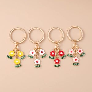 Détails macro de quatre porte-clés fleurs en émail coloré en jaune, blanc, rouge et rose