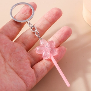 Detail view of a pink cherry blossom lollipop keychain with glitter resin petals