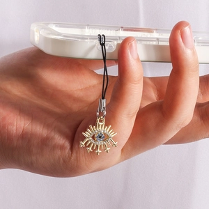 Close-up of golden Evil Eye phone charm with blue crystal and white cubic zirconia