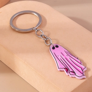 Detail shot of a pink ghost keychain with silver metal ring on a textured block
