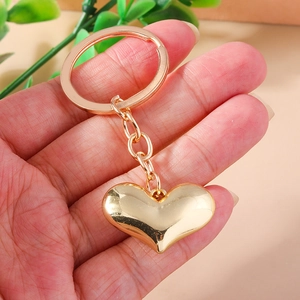 Detailed view of a golden 3D heart keychain with a polished mirror finish on a metal ring