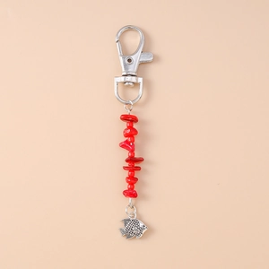 Close-up of ocean-themed keychain with red beads and silver fish charm on pink background