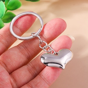 Polished silver heart-shaped metal keychain with a minimalist ring and chain on hands