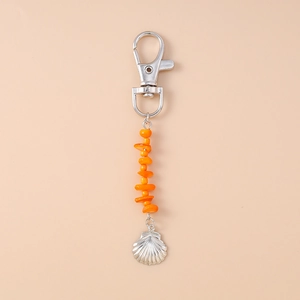 Detailed view of silver shell pendant with bright orange resin stones on keychain