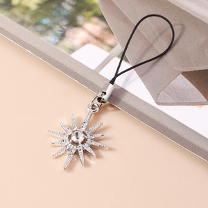 Close-up of a silver starburst phone charm with sparkling rhinestones and black lanyard