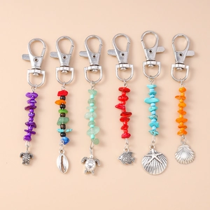 Set of six colorful stone bead keychains with silver ocean animal charms on pink background