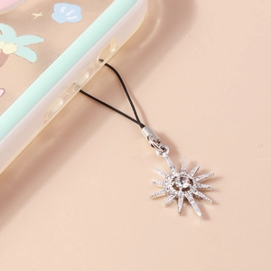 Detail of silver starburst phone charm encrusted with rhinestones on a pink background