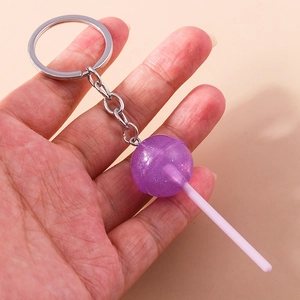 Close-up of a purple glitter lollipop keychain held in hand showing resin texture