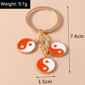 Vue détaillée du porte-clés yin yang doré avec des pendentifs tai chi en forme de cœur